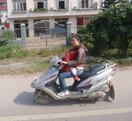 Mom and young child, in a front loader, on the go.